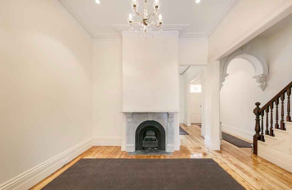 メルボルンにあるお手頃価格の中くらいなヴィクトリアン調のおしゃれな独立型ダイニング (白い壁、淡色無垢フローリング、標準型暖炉、石材の暖炉まわり、ベージュの床) の写真