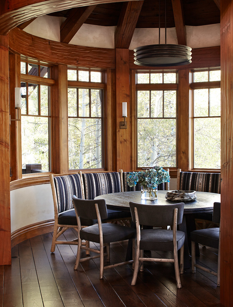 Cette image montre une salle à manger ouverte sur la cuisine chalet avec un mur blanc et parquet foncé.