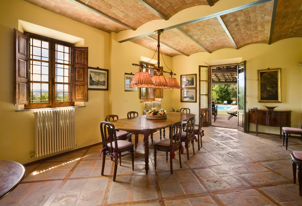 Dining room - cottage terra-cotta tile and brown floor dining room idea in New York with yellow walls