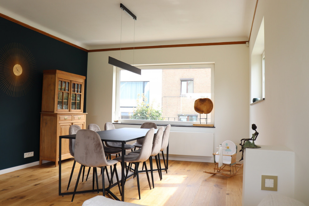 Immagine di una sala da pranzo aperta verso il soggiorno minimalista di medie dimensioni con pareti verdi, pavimento in legno massello medio, nessun camino, pavimento marrone e soffitto a volta