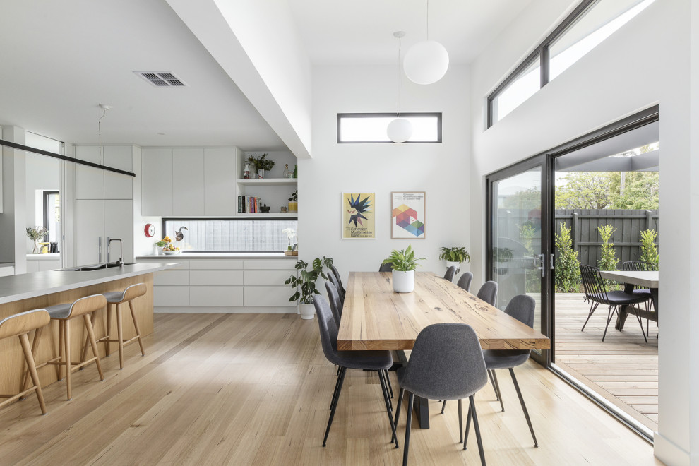 This is an example of a contemporary dining room in Melbourne with white walls, light hardwood flooring and beige floors.