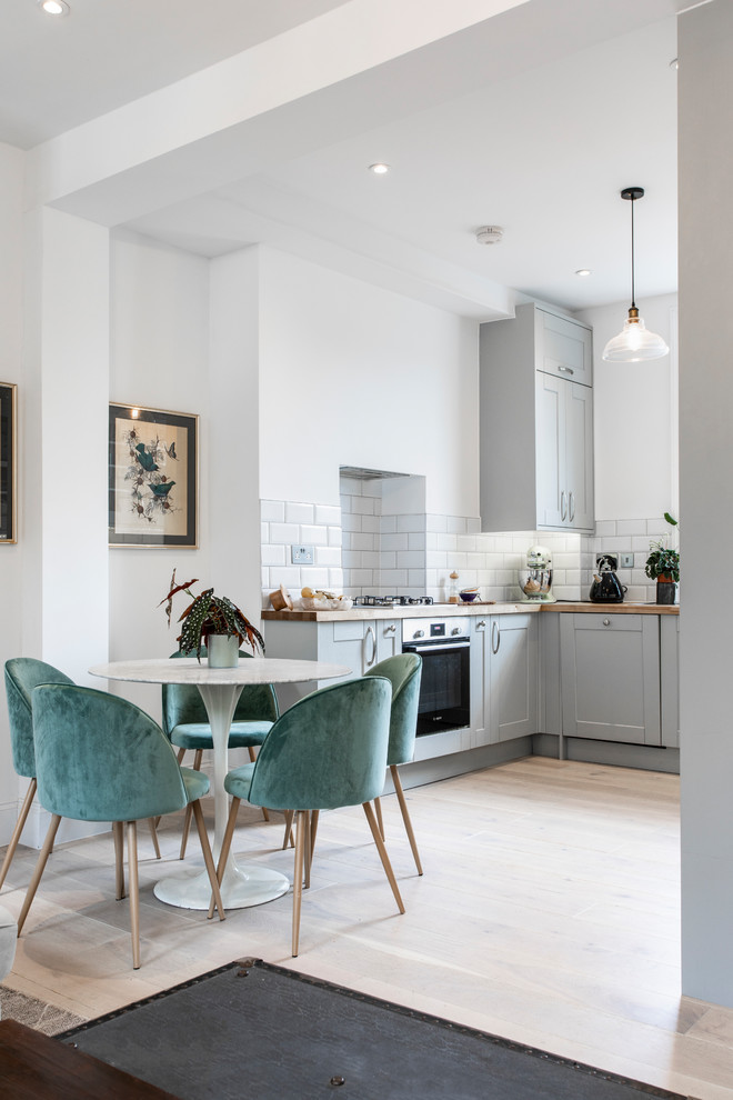 Klassische Wohnküche ohne Kamin mit weißer Wandfarbe, hellem Holzboden und beigem Boden in London