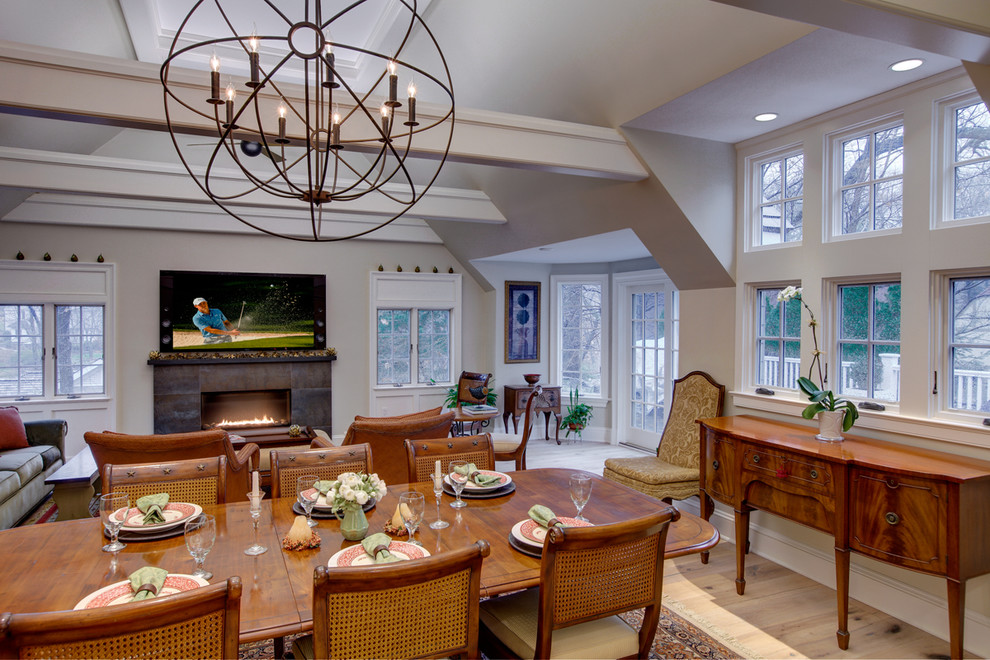 Large traditional open plan dining room in New York with beige walls, light hardwood flooring, a standard fireplace and a metal fireplace surround.