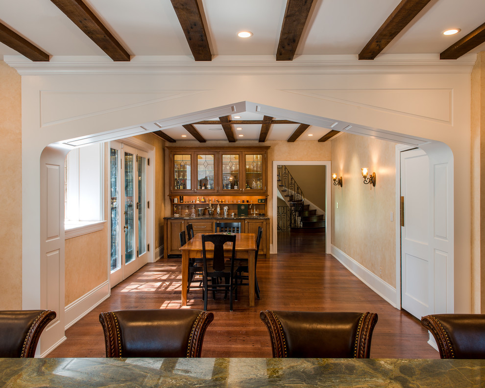 Imagen de comedor clásico abierto con paredes beige y suelo de madera en tonos medios