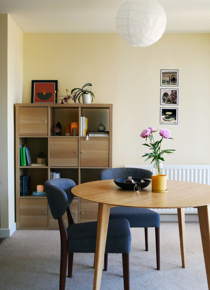На фото: гостиная-столовая среднего размера в скандинавском стиле с желтыми стенами, ковровым покрытием и бежевым полом без камина с