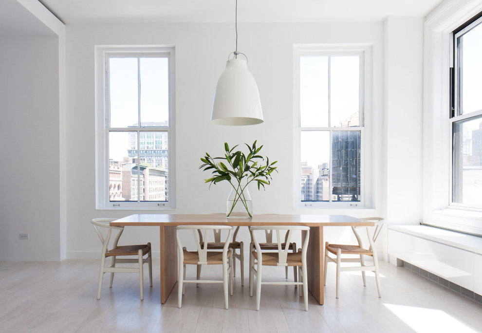 Example of a danish light wood floor and white floor dining room design in New York with white walls