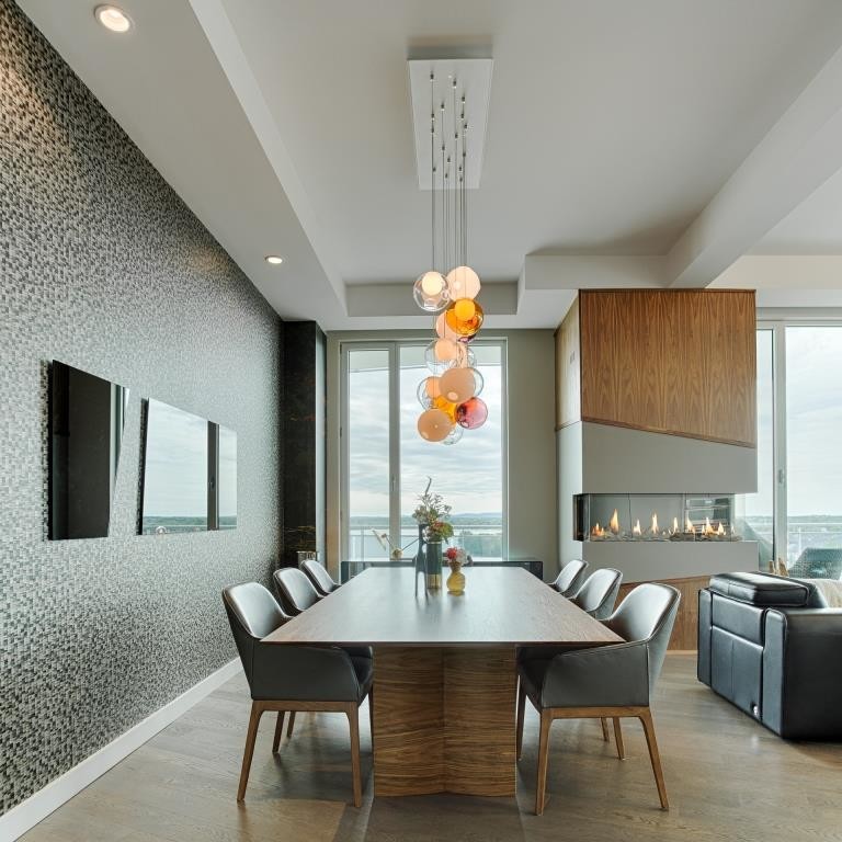 Offenes, Mittelgroßes Modernes Esszimmer mit grauer Wandfarbe, dunklem Holzboden, Eckkamin, Kaminumrandung aus Holz und braunem Boden in Montreal