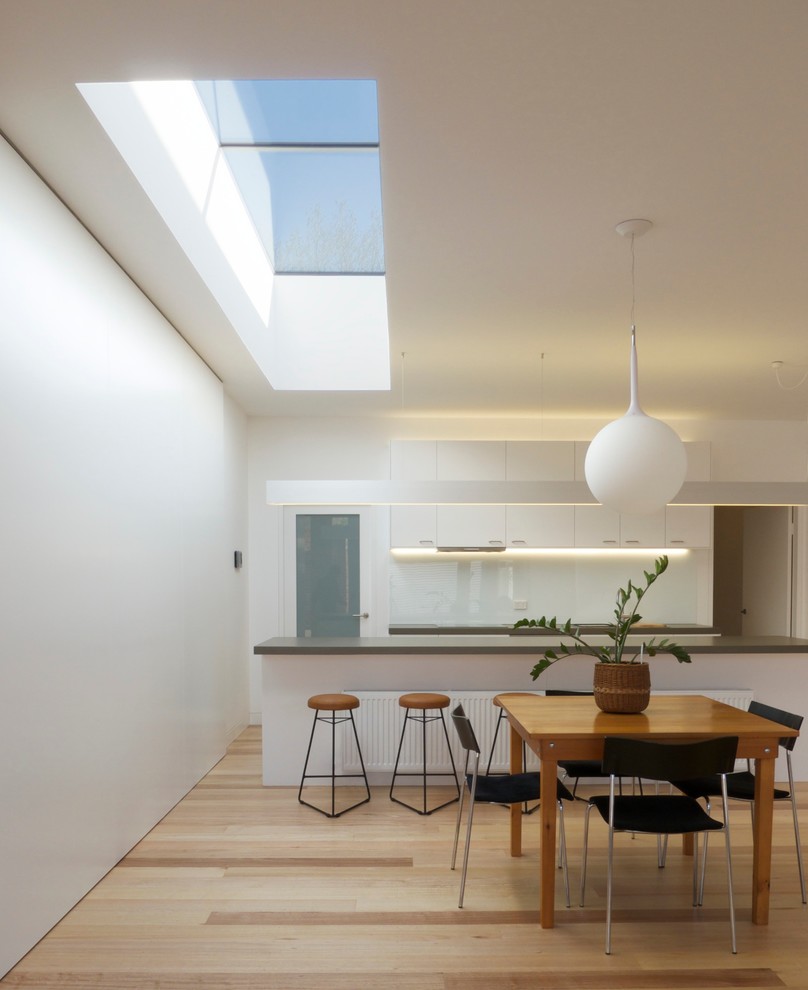 Exemple d'une salle à manger ouverte sur la cuisine tendance avec un mur blanc et un sol en bois brun.