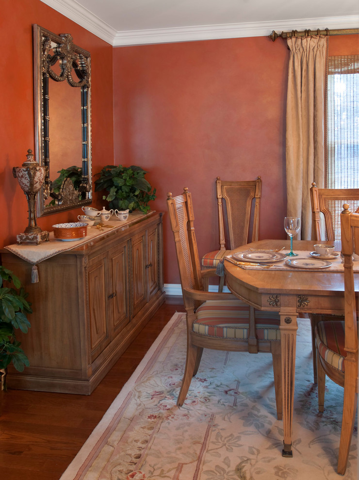 Cette image montre une grande salle à manger traditionnelle fermée avec un mur orange, parquet foncé et aucune cheminée.