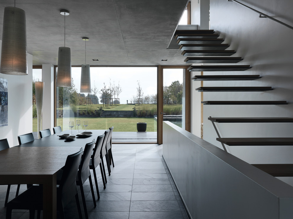 Стильный дизайн: столовая в стиле модернизм с белыми стенами и полом из сланца - последний тренд
