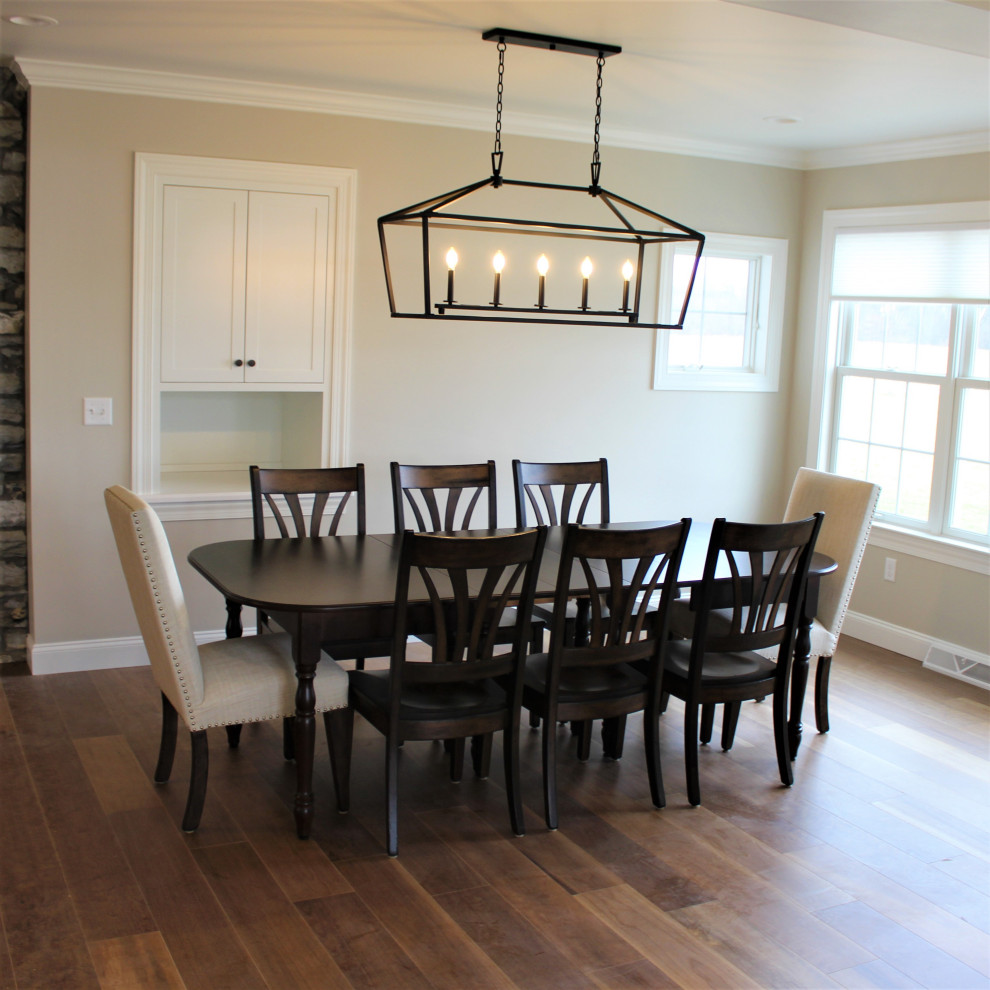 Cette photo montre une salle à manger ouverte sur la cuisine nature avec un mur beige, un sol en bois brun et un sol marron.