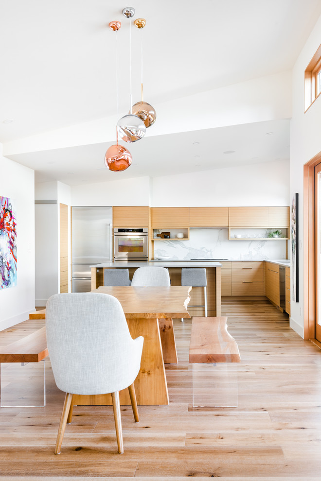 Ispirazione per una sala da pranzo aperta verso la cucina chic con pareti bianche, parquet chiaro e pavimento beige