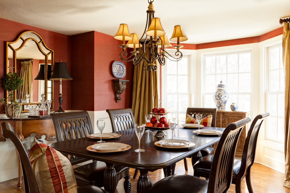 Aménagement d'une salle à manger classique avec un mur rouge et un sol en bois brun.