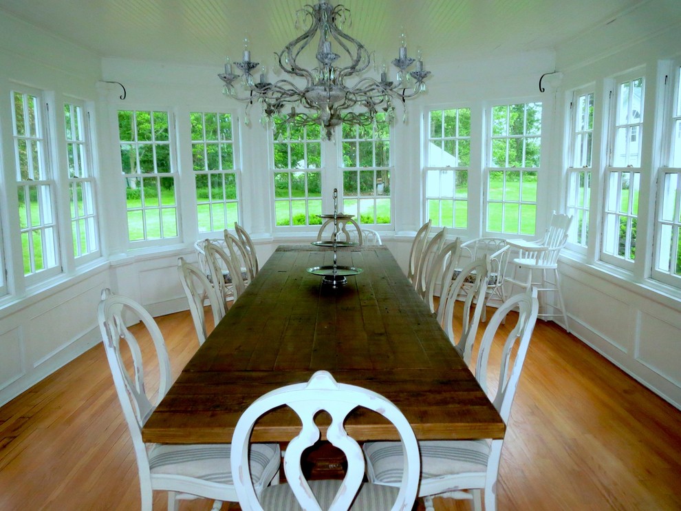 Cette photo montre une grande salle à manger nature fermée avec un mur blanc, un sol en bois brun et aucune cheminée.