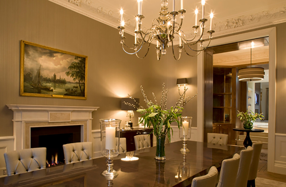 Design ideas for a large traditional enclosed dining room in London with beige walls, medium hardwood flooring, a standard fireplace, a stone fireplace surround and brown floors.