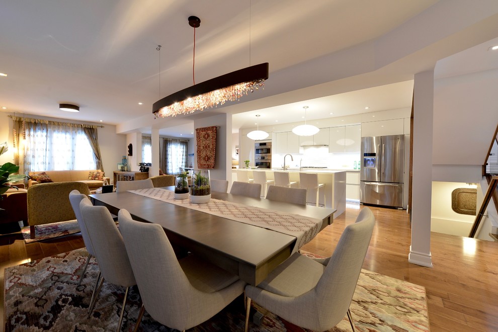 Idée de décoration pour une salle à manger ouverte sur le salon minimaliste de taille moyenne avec un mur blanc, parquet foncé et un sol marron.