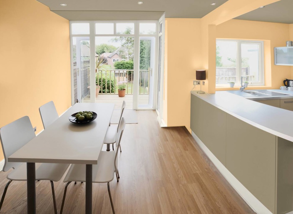 Cette photo montre une salle à manger ouverte sur la cuisine tendance de taille moyenne avec un mur jaune, un sol en bois brun et aucune cheminée.