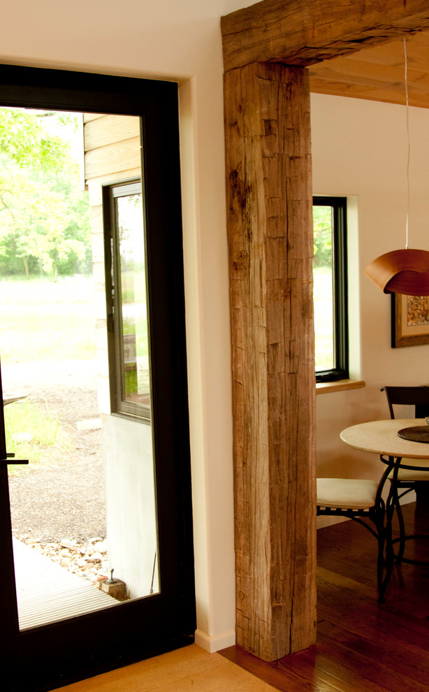 Cette image montre une salle à manger ouverte sur la cuisine minimaliste de taille moyenne avec un mur blanc, un sol en bois brun, aucune cheminée et un sol marron.