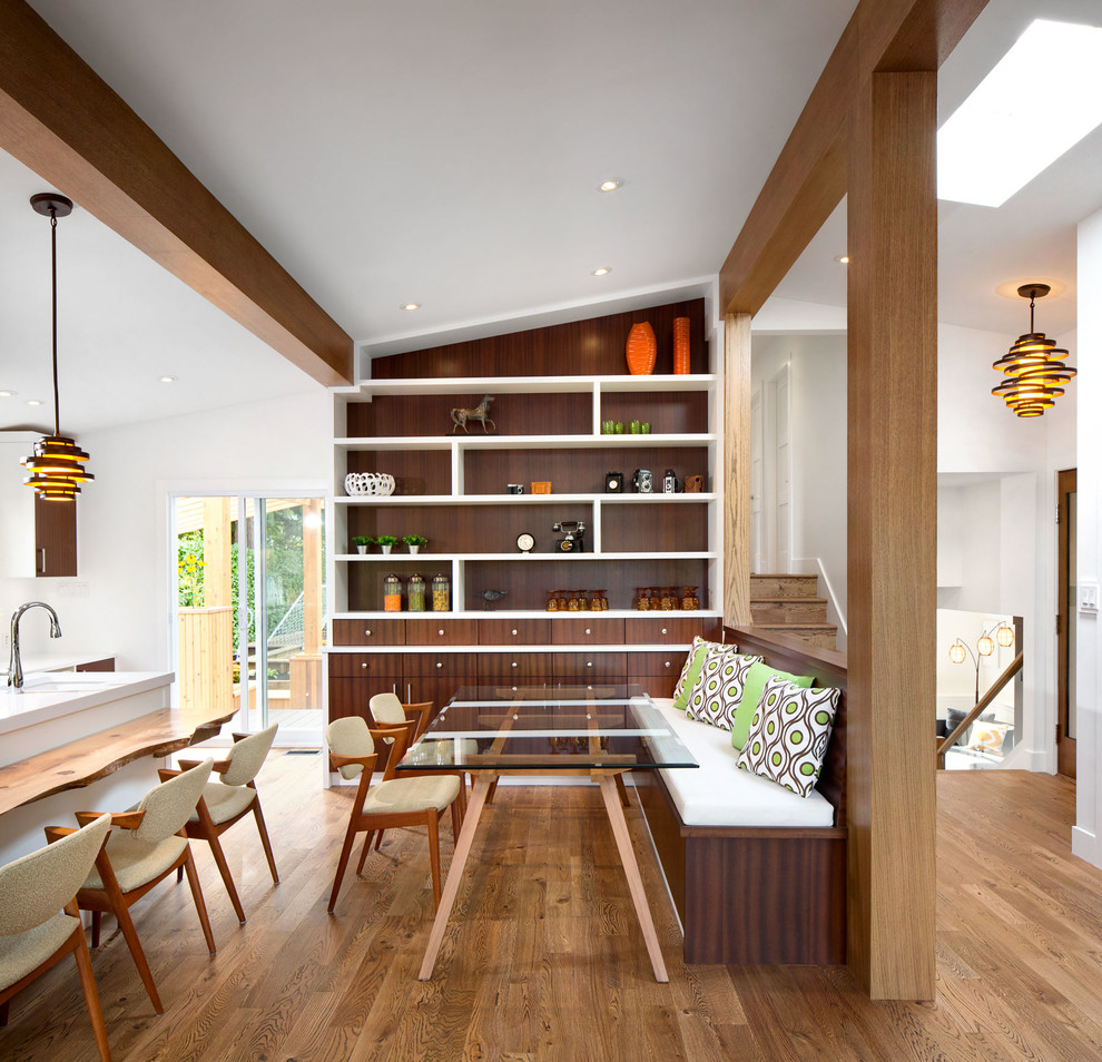 Aménagement d'une salle à manger ouverte sur la cuisine rétro avec un mur blanc et un sol en bois brun.