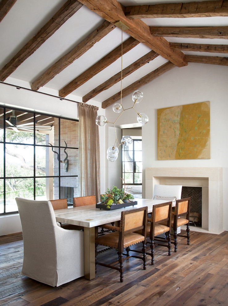 Design ideas for a mediterranean dining room in Austin with white walls, dark hardwood flooring and a standard fireplace.