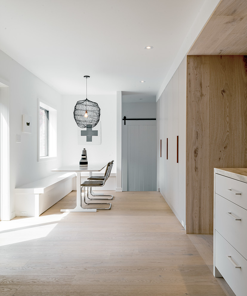 Mittelgroße Moderne Wohnküche ohne Kamin mit weißer Wandfarbe, hellem Holzboden und braunem Boden in Toronto