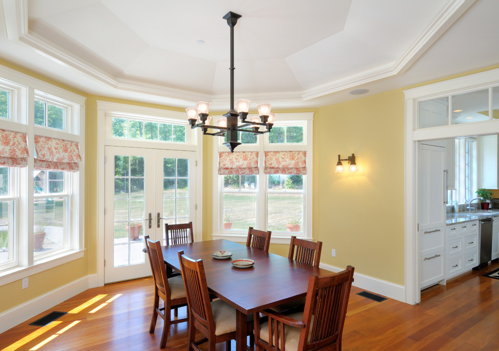Immagine di una sala da pranzo stile americano con pareti gialle e pavimento in legno massello medio