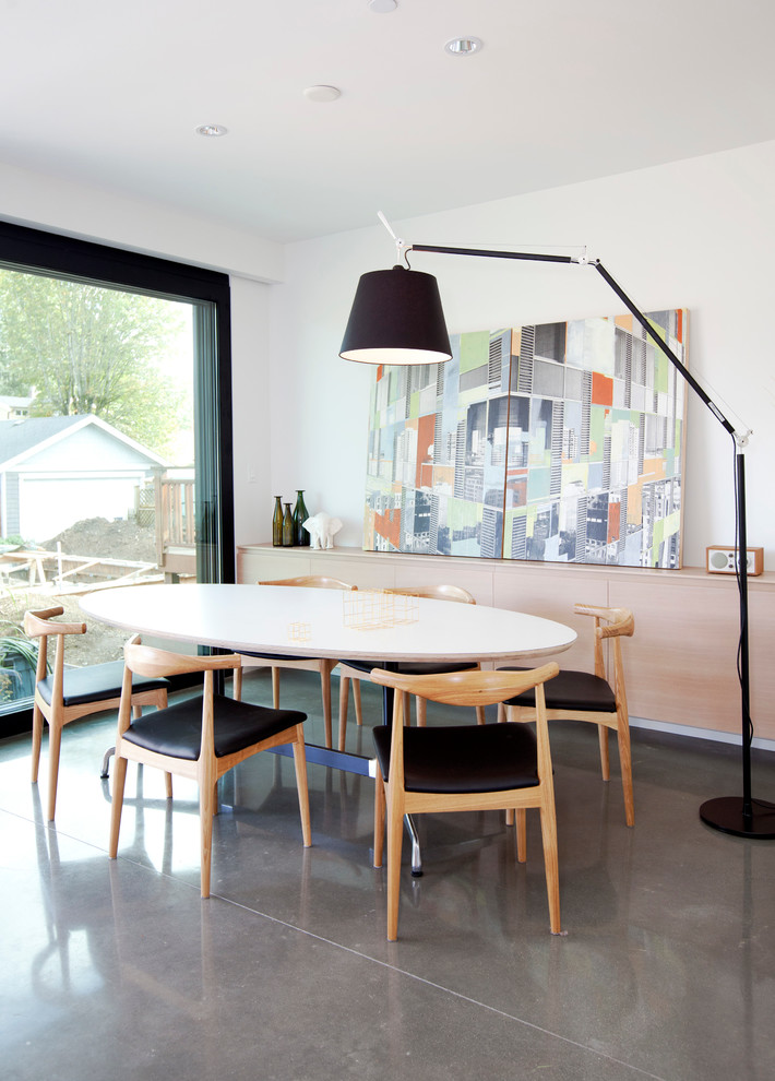 На фото: столовая в скандинавском стиле с белыми стенами, бетонным полом и серым полом с