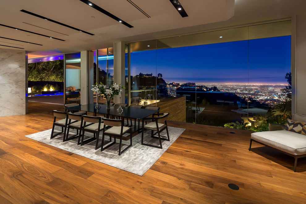 Offenes, Geräumiges Modernes Esszimmer mit grauer Wandfarbe, braunem Holzboden, Gaskamin und Kaminumrandung aus Stein in Los Angeles