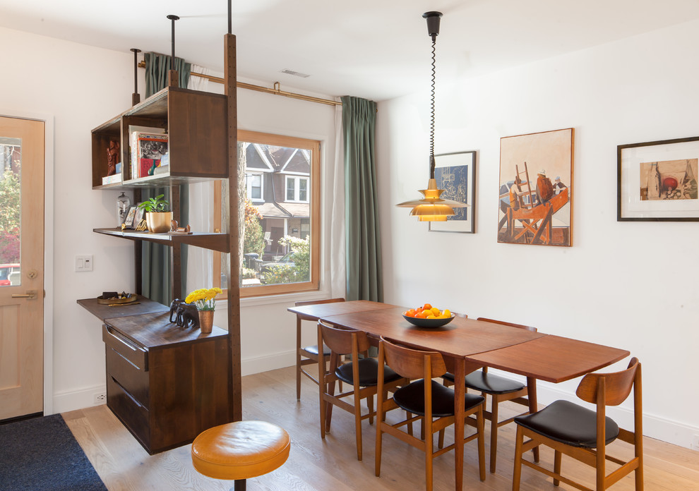 Cette image montre une salle à manger ouverte sur le salon vintage de taille moyenne avec un mur blanc, parquet clair, aucune cheminée et un sol marron.