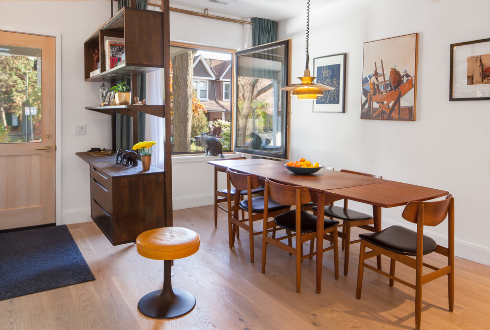 Immagine di una sala da pranzo aperta verso il soggiorno minimalista di medie dimensioni con pareti bianche, parquet chiaro, nessun camino e pavimento marrone