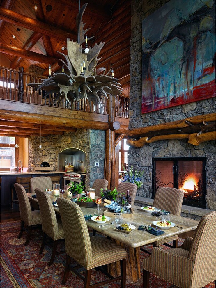 Aménagement d'une grande salle à manger ouverte sur la cuisine montagne avec une cheminée standard, un mur marron, parquet foncé, un manteau de cheminée en pierre et un sol marron.