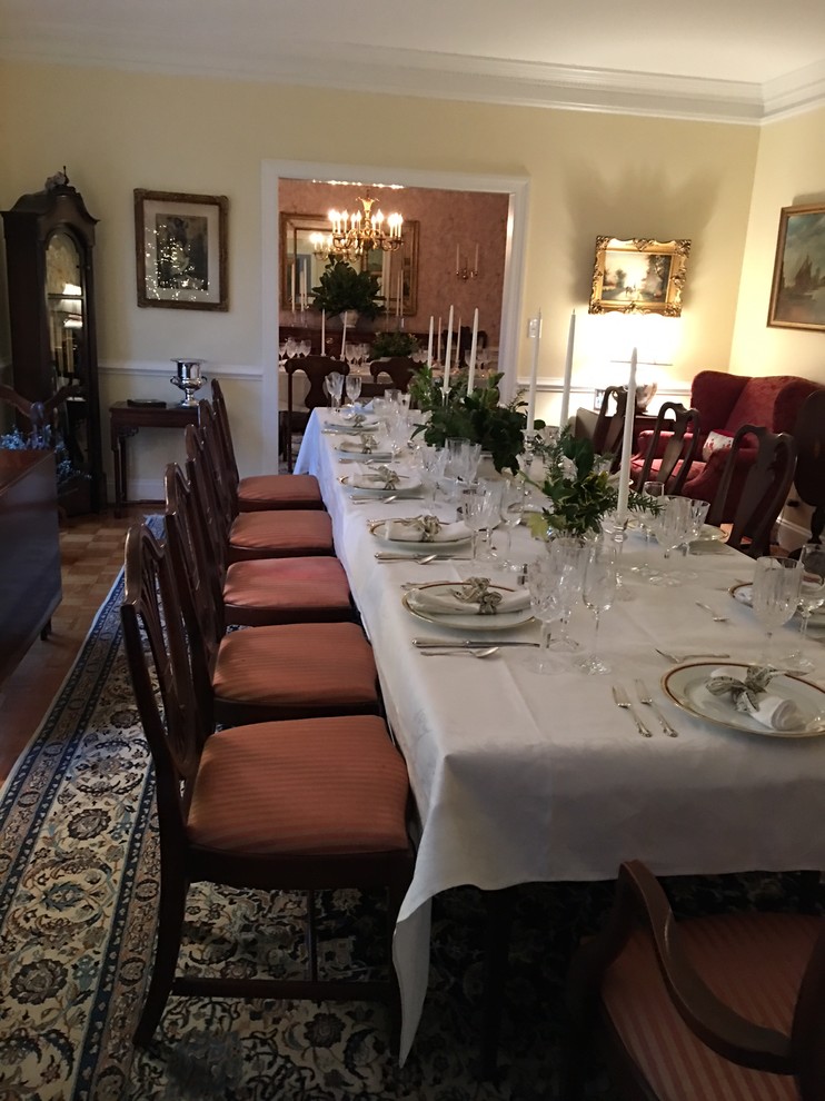 Medium sized traditional enclosed dining room in DC Metro with yellow walls, light hardwood flooring, a wooden fireplace surround and brown floors.