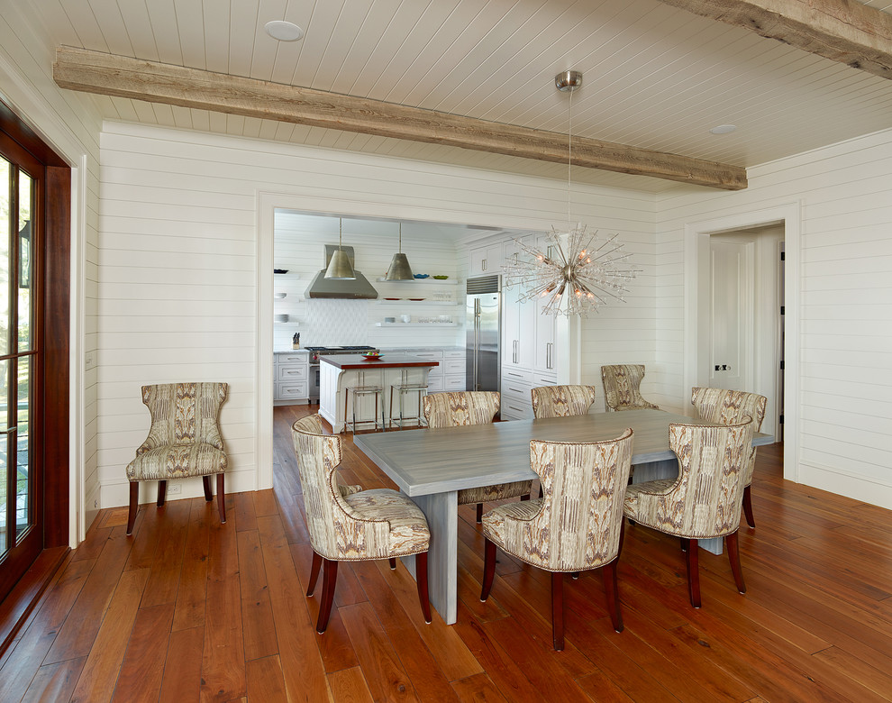 Aménagement d'une salle à manger bord de mer avec un mur blanc et un sol en bois brun.