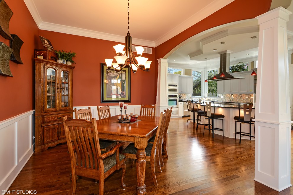 Exemple d'une grande salle à manger ouverte sur la cuisine craftsman avec un mur rouge, parquet foncé et aucune cheminée.