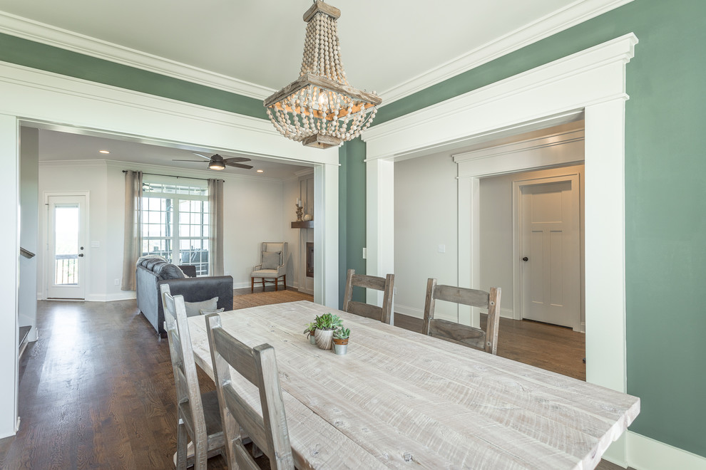 Inspiration pour une salle à manger ouverte sur le salon rustique avec un mur vert, parquet clair et un sol marron.