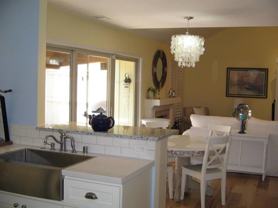 Cette photo montre une salle à manger ouverte sur la cuisine bord de mer de taille moyenne avec un mur bleu, un sol en bois brun, une cheminée standard et un manteau de cheminée en carrelage.