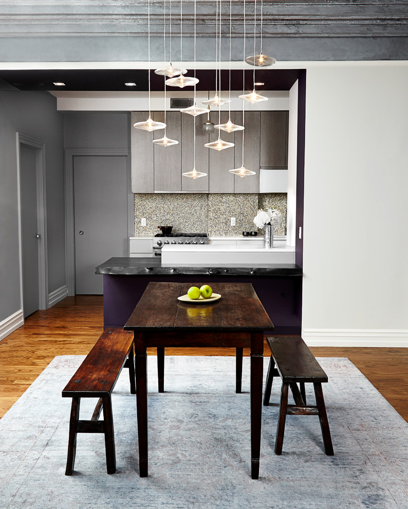 Cette photo montre une salle à manger ouverte sur la cuisine tendance de taille moyenne avec un mur gris, un sol en bois brun et aucune cheminée.