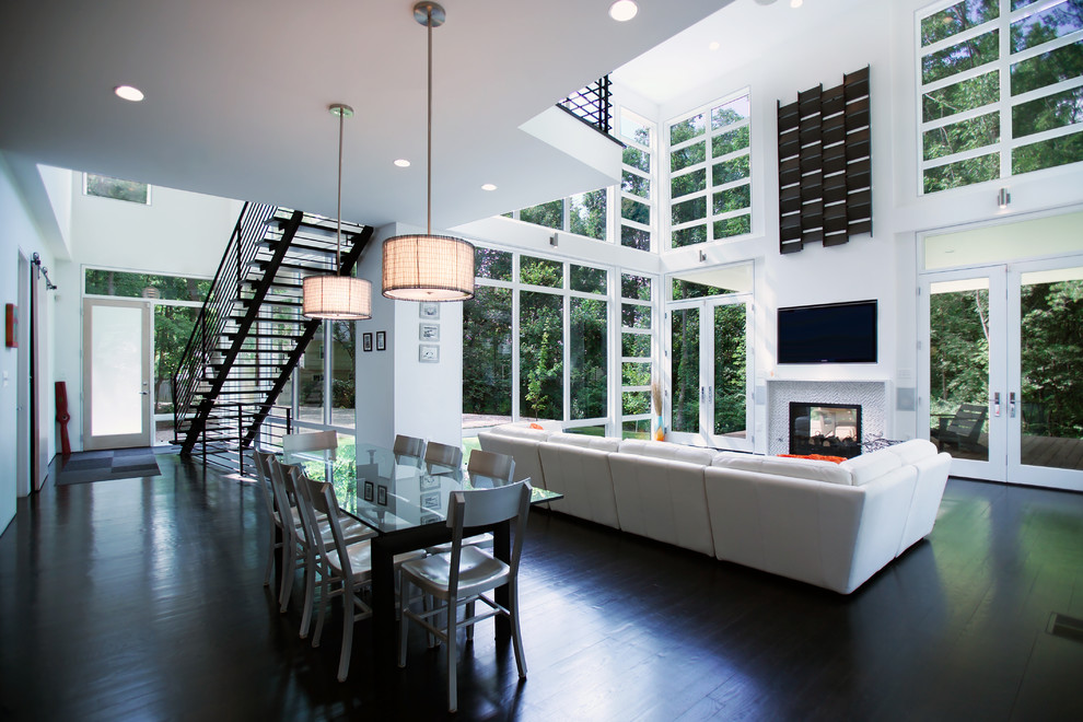 Cette image montre une salle à manger ouverte sur le salon design avec un mur blanc et un sol noir.
