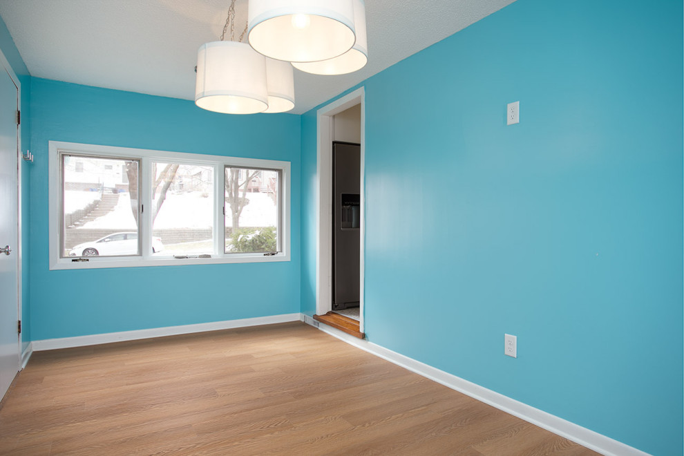 Foto di una sala da pranzo minimalista chiusa e di medie dimensioni con pareti blu, pavimento in laminato, nessun camino e pavimento marrone