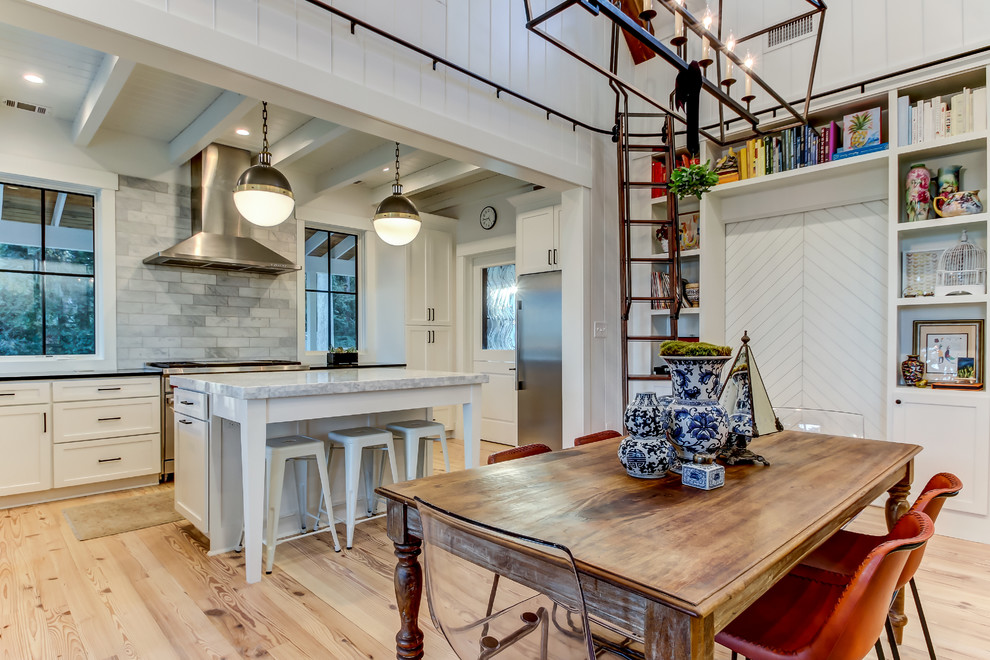 Cette photo montre une salle à manger ouverte sur le salon tendance avec un mur blanc, parquet clair, une cheminée standard, un manteau de cheminée en brique et un sol marron.