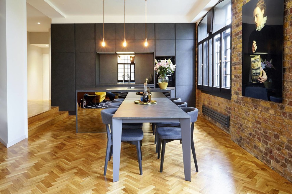 This is an example of a large contemporary open plan dining room in London with medium hardwood flooring.