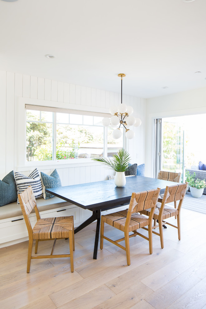 Foto di una sala da pranzo aperta verso la cucina stile marino con pareti bianche, parquet chiaro e pavimento beige