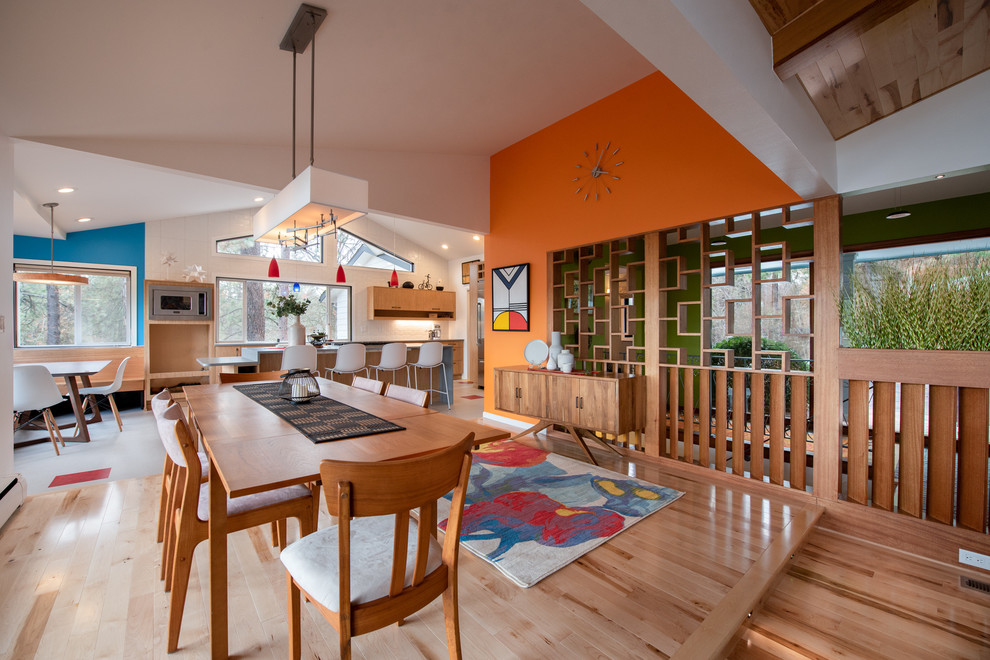Cette image montre une salle à manger vintage avec un mur orange, un sol en bois brun et un sol marron.