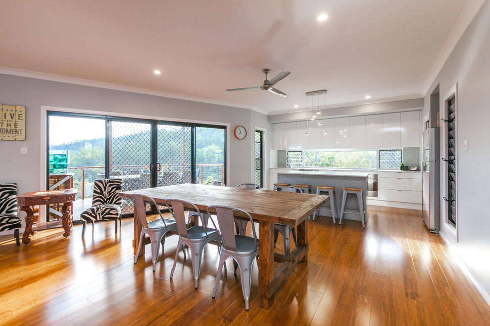 Foto di una sala da pranzo aperta verso la cucina design di medie dimensioni con pareti grigie, pavimento in legno massello medio e pavimento marrone