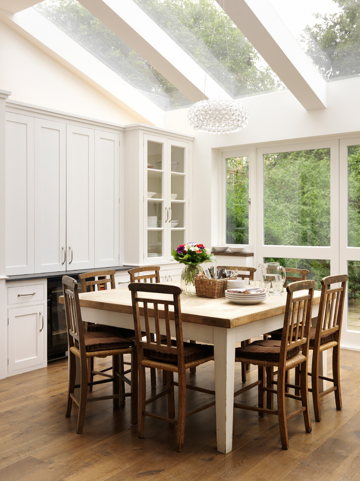 Design ideas for a traditional dining room in London with white walls, medium hardwood flooring and brown floors.