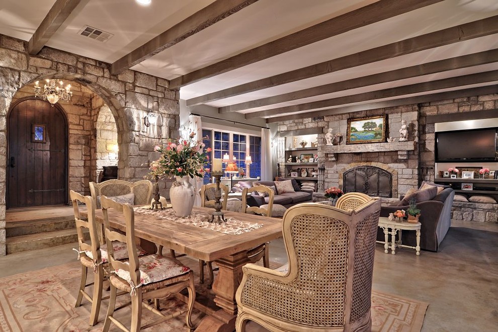 Réalisation d'une très grande salle à manger ouverte sur le salon style shabby chic avec sol en béton ciré et un manteau de cheminée en pierre.