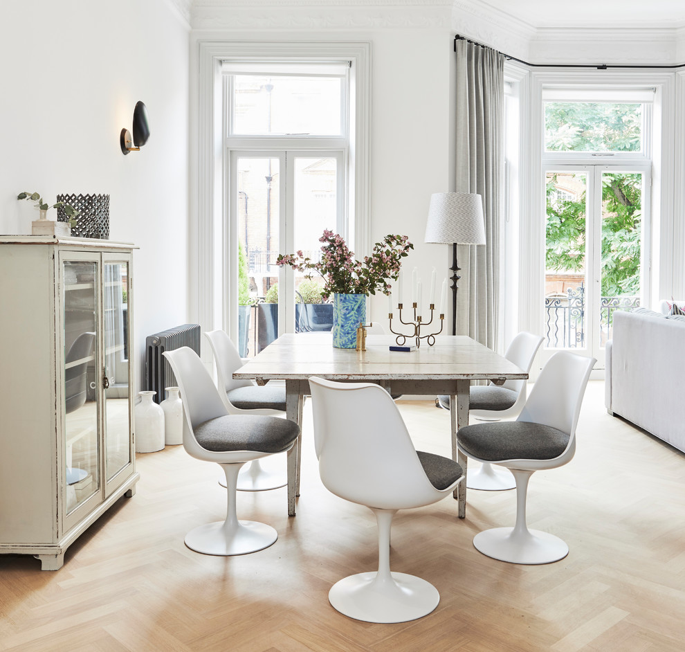 Scandi dining room in London with white walls, light hardwood flooring and beige floors.