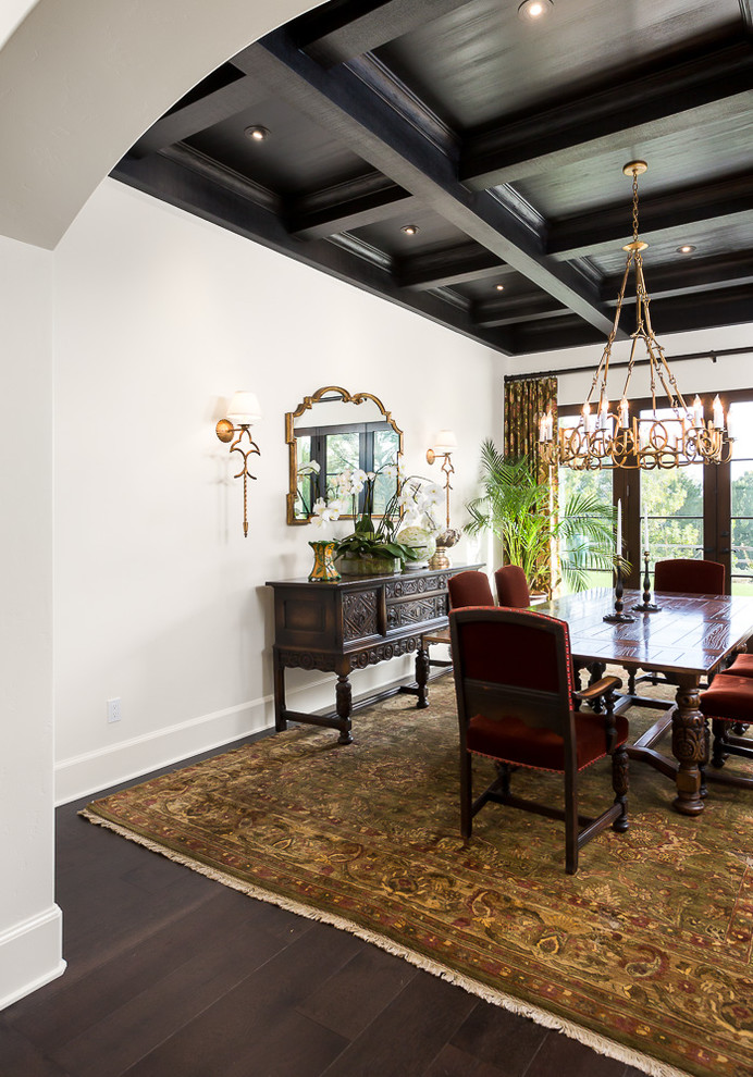 Mediterranean enclosed dining room in Los Angeles with white walls, dark hardwood flooring and feature lighting.