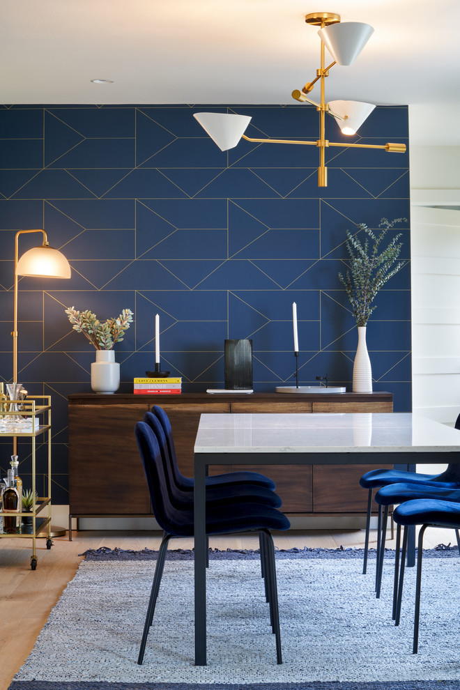Cette image montre une salle à manger ouverte sur la cuisine minimaliste de taille moyenne avec un mur bleu, parquet clair, éclairage et aucune cheminée.