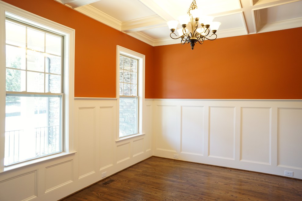 Foto di una sala da pranzo minimal chiusa e di medie dimensioni con pareti arancioni, pavimento in legno massello medio e nessun camino